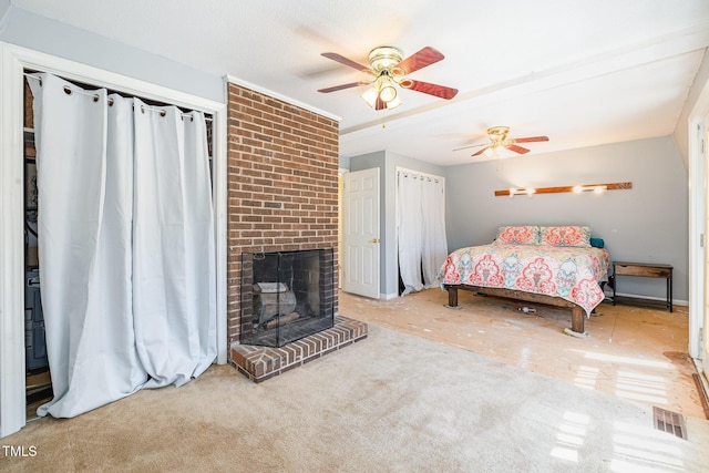 bedroom with a brick fireplace, visible vents, and a ceiling fan