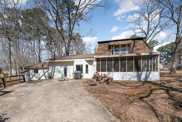 view of front of home with a sunroom, aphalt driveway, and roof with shingles