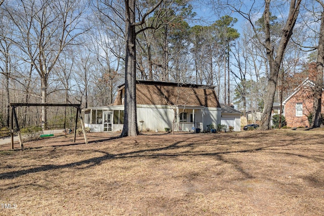 back of property with a garage, a yard, and a sunroom