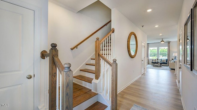 stairs with baseboards, wood finished floors, and recessed lighting