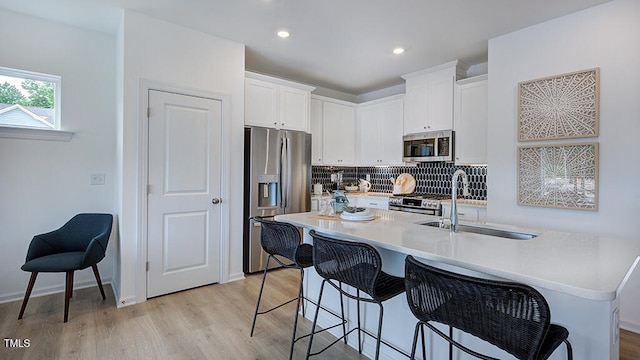 kitchen with a sink, white cabinetry, light countertops, appliances with stainless steel finishes, and tasteful backsplash