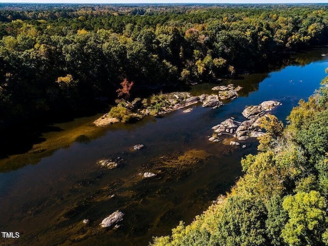 birds eye view of property with a water view and a wooded view