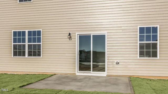 property entrance featuring a lawn and a patio