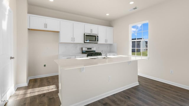 kitchen featuring a center island with sink, stainless steel appliances, light countertops, visible vents, and white cabinetry