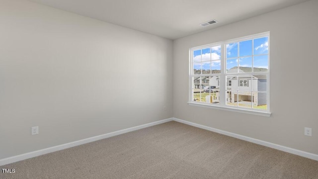 spare room featuring carpet, visible vents, and baseboards