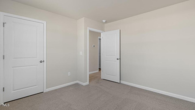 unfurnished bedroom featuring baseboards and light colored carpet