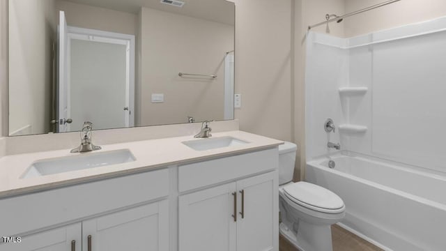 bathroom with double vanity, shower / tub combination, toilet, and a sink