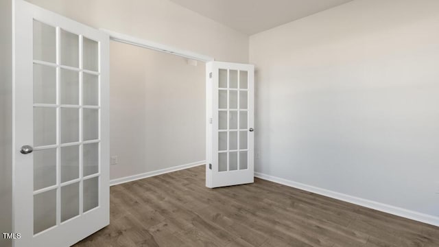 empty room featuring dark wood-style flooring, french doors, and baseboards