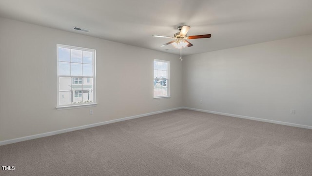 spare room with light carpet, baseboards, visible vents, and ceiling fan