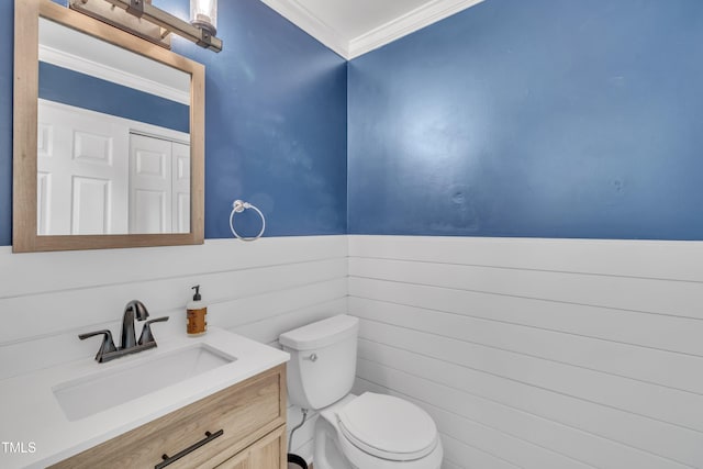 bathroom featuring a wainscoted wall, ornamental molding, vanity, and toilet