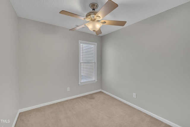 spare room with a textured ceiling, baseboards, a ceiling fan, and light colored carpet