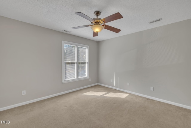 carpeted spare room featuring visible vents, a textured ceiling, and baseboards