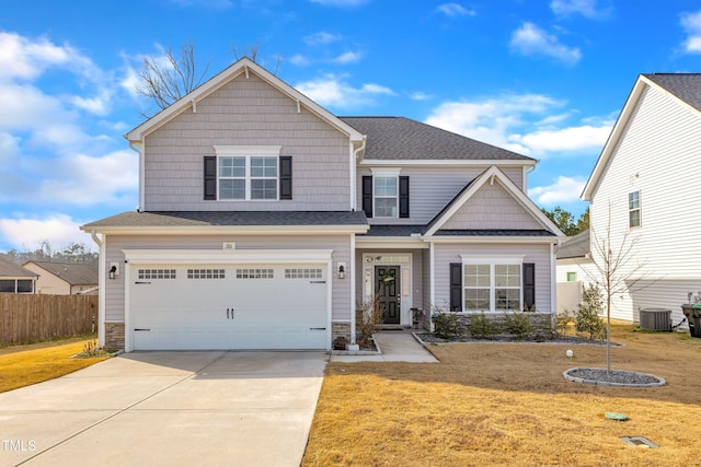 craftsman-style house featuring an attached garage, a front yard, central AC, fence, and driveway