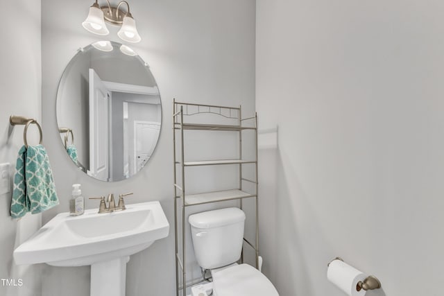 half bathroom with a chandelier, a sink, and toilet