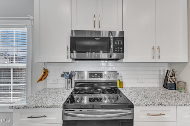 kitchen featuring stainless steel appliances, a healthy amount of sunlight, white cabinetry, and decorative backsplash