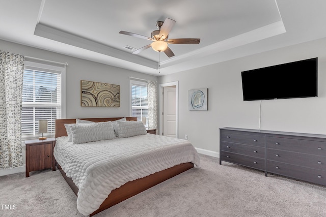 carpeted bedroom featuring a raised ceiling, multiple windows, and visible vents