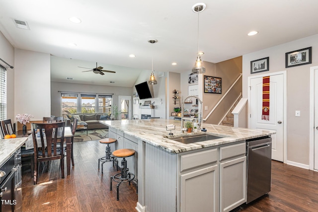 kitchen featuring visible vents, open floor plan, an island with sink, a kitchen bar, and pendant lighting