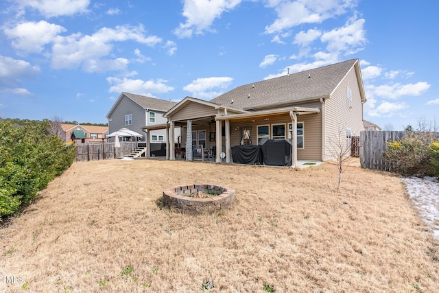 rear view of house with an outdoor fire pit, a fenced backyard, a patio, and a lawn