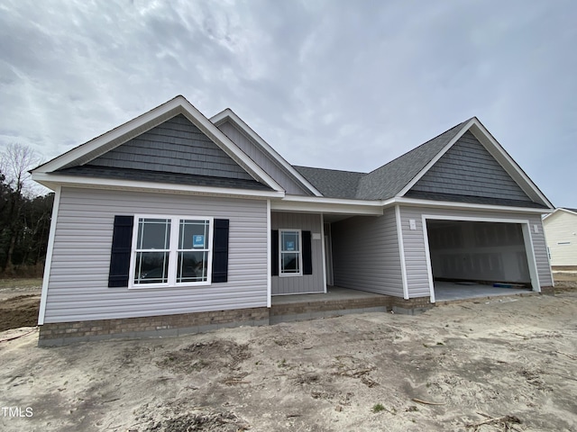 view of front facade with a garage and a shingled roof