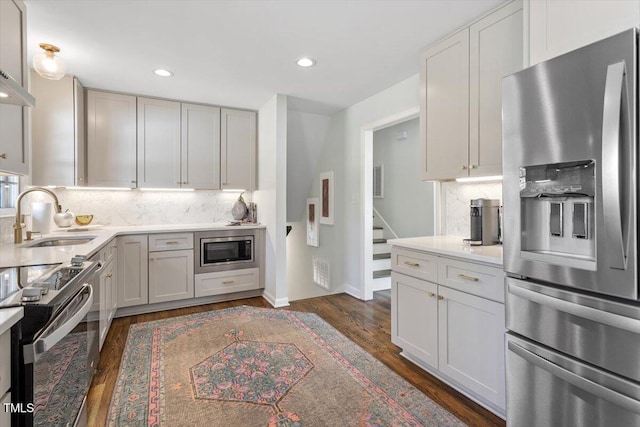 kitchen featuring light countertops, appliances with stainless steel finishes, a sink, and tasteful backsplash