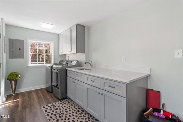 washroom with cabinet space, electric panel, washer and clothes dryer, dark wood-style floors, and a sink