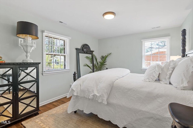 bedroom with wood finished floors, visible vents, and baseboards