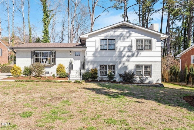 split level home featuring crawl space, brick siding, a chimney, and a front yard