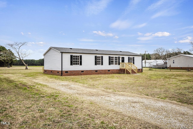 manufactured / mobile home with a shingled roof, crawl space, and a front lawn