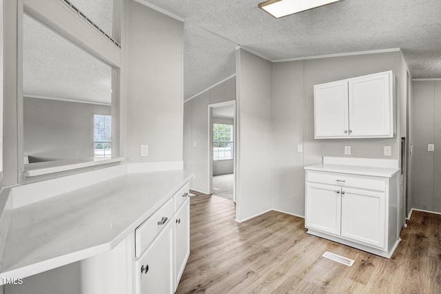 kitchen with ornamental molding, light wood-type flooring, light countertops, and white cabinetry