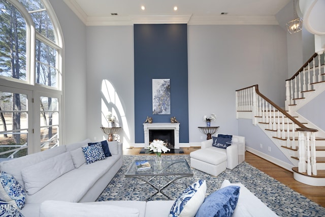 living room featuring stairway, ornamental molding, a fireplace, and wood finished floors