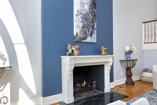 living area featuring visible vents, a fireplace, baseboards, and wood finished floors