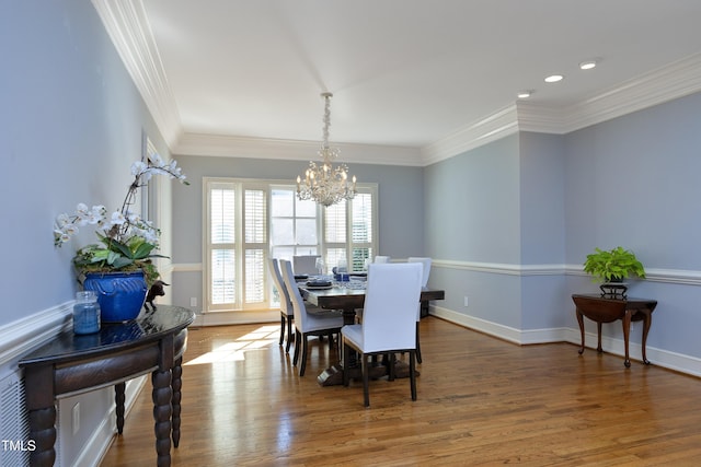 dining space with crown molding, a notable chandelier, wood finished floors, and baseboards