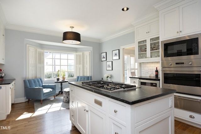 kitchen with a warming drawer, dark countertops, appliances with stainless steel finishes, and ornamental molding