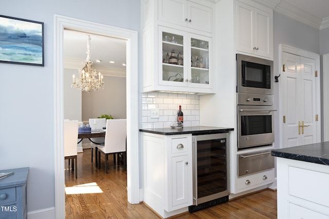 kitchen featuring beverage cooler, built in microwave, ornamental molding, dark countertops, and a warming drawer