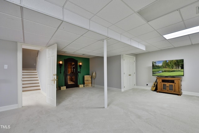 finished basement featuring carpet flooring, a paneled ceiling, baseboards, and stairs