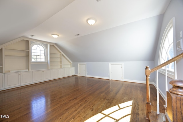 additional living space featuring built in features, lofted ceiling, dark wood-type flooring, and baseboards