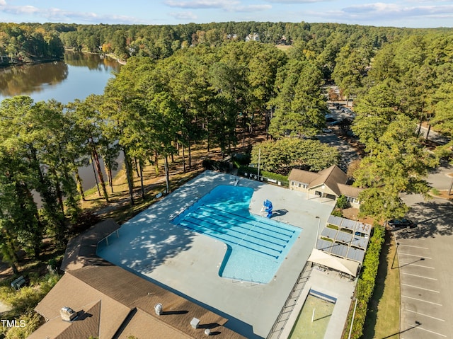 view of pool with a wooded view and a water view