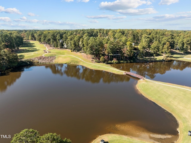 drone / aerial view with golf course view, a view of trees, and a water view