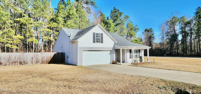 traditional home with driveway, an attached garage, fence, a porch, and a front yard