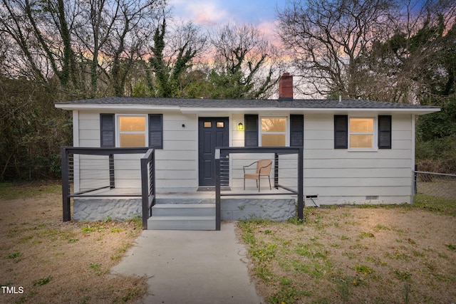 view of front facade with fence, roof with shingles, covered porch, crawl space, and a chimney