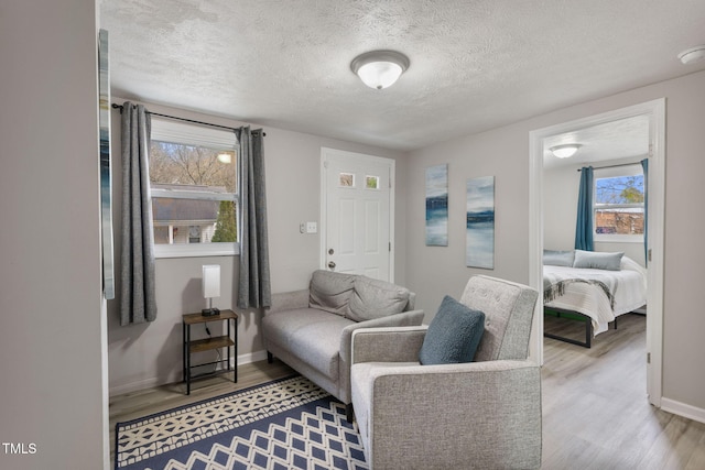 living area featuring wood finished floors, baseboards, and a textured ceiling