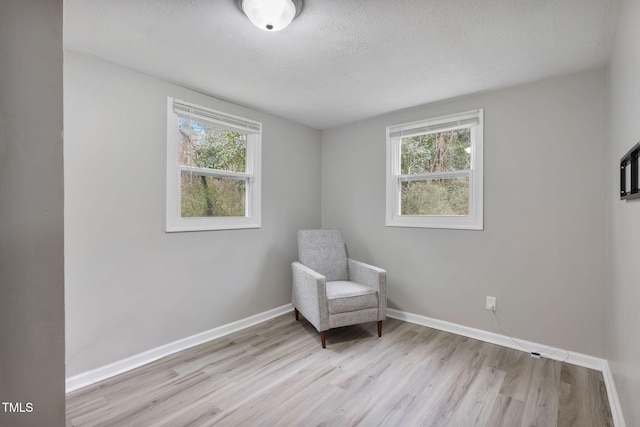 living area featuring light wood-style flooring, plenty of natural light, and baseboards