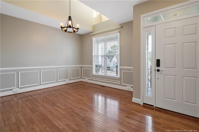 entryway with a wainscoted wall, a chandelier, and hardwood / wood-style floors