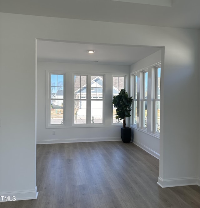 empty room featuring baseboards and dark wood-type flooring