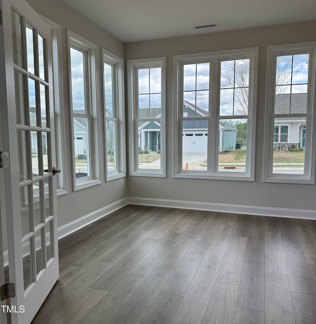 unfurnished sunroom featuring visible vents, wood finished floors, and baseboards