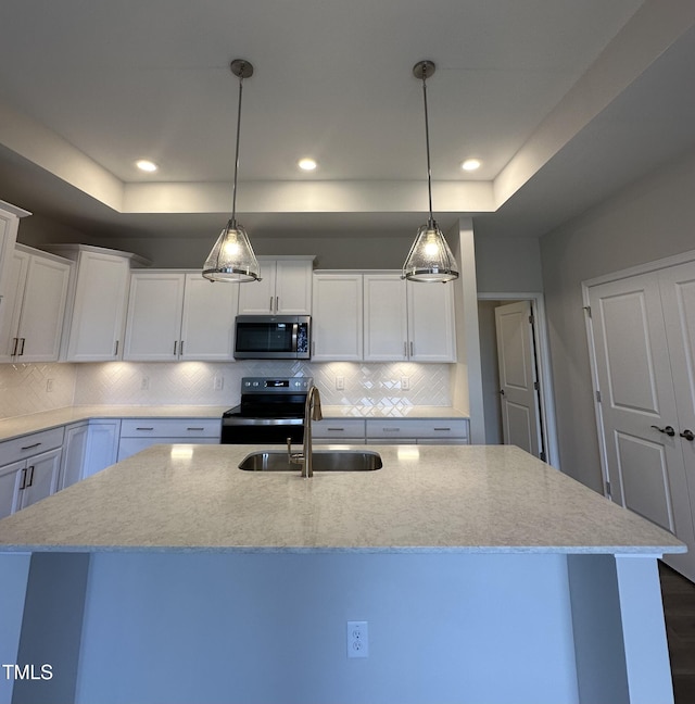 kitchen with stainless steel microwave, electric stove, a sink, light stone counters, and white cabinetry