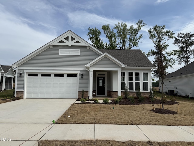 craftsman-style house featuring brick siding, central AC unit, and concrete driveway