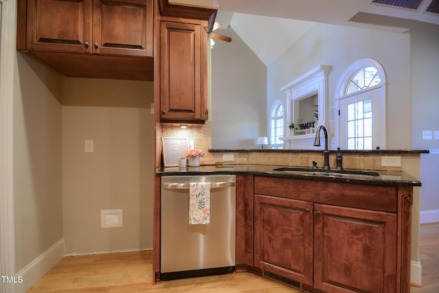 kitchen with decorative backsplash, dark stone counters, dishwasher, a peninsula, and a sink