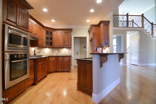 kitchen featuring stainless steel appliances, a breakfast bar, a sink, decorative backsplash, and crown molding