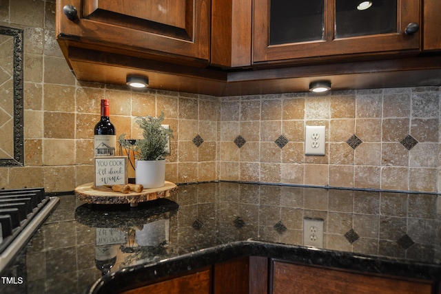 interior details with dark stone counters, glass insert cabinets, and stainless steel gas cooktop